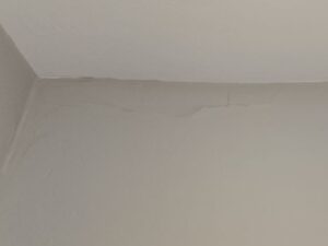 Drywall settling damage with crooked paint before photo